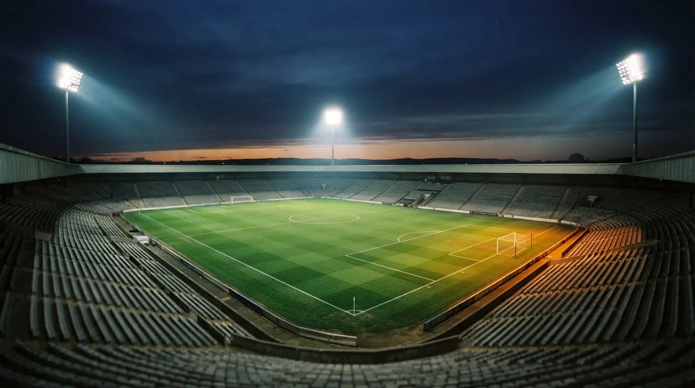 Een leeg voetbalstadion met lichtmasten bij schemering