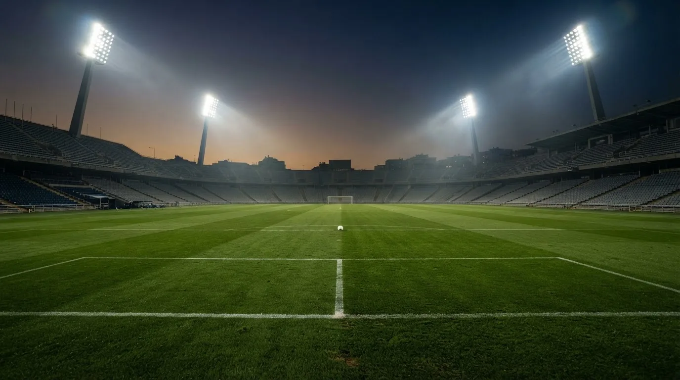 Een leeg voetbalstadion met lichtmasten bij schemering