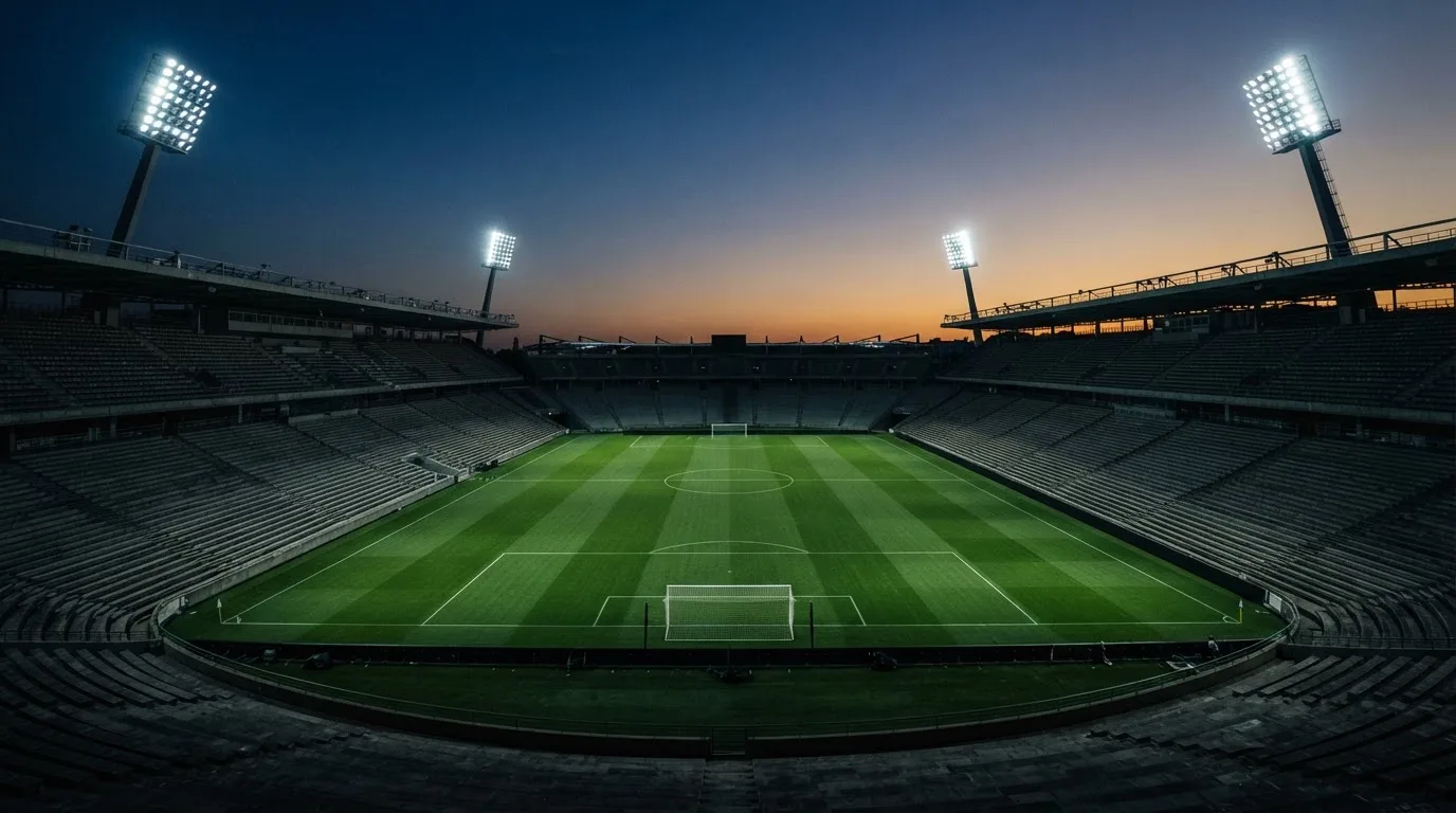 Een leeg voetbalstadion met lichtmasten bij schemering