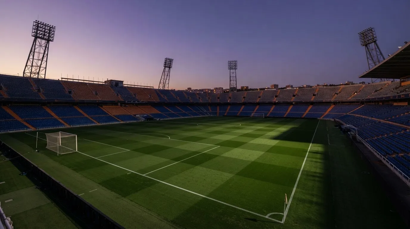 Een leeg voetbalstadion met lichtmasten bij schemering