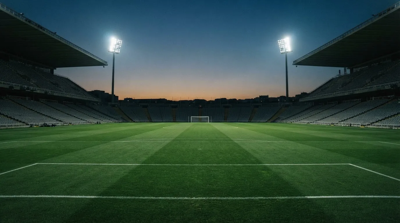 Een leeg voetbalstadion met lichtmasten bij schemering