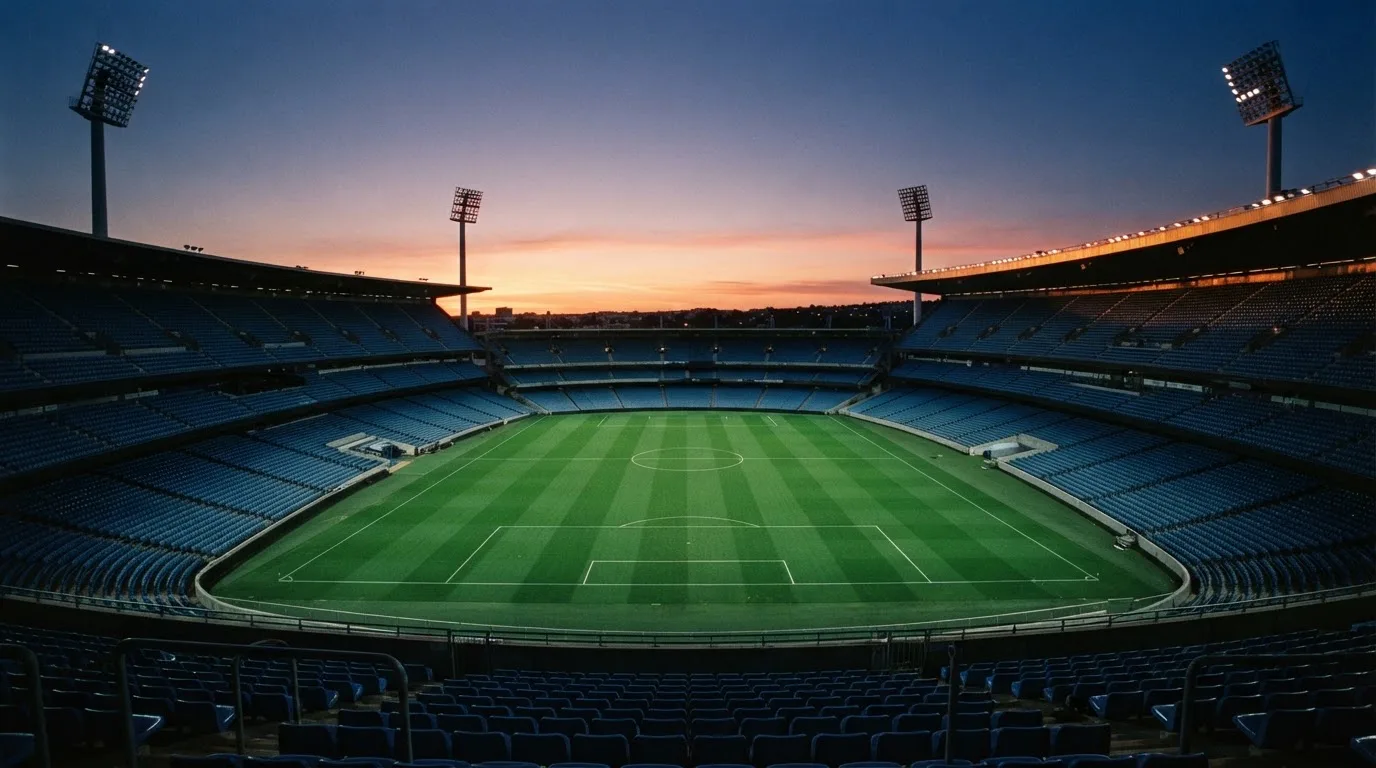 Een leeg voetbalstadion met lichtmasten bij schemering