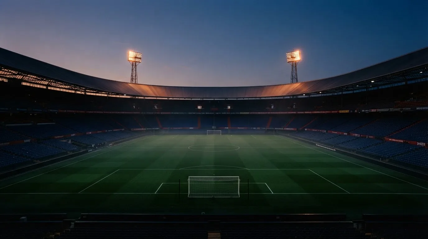 Een leeg voetbalstadion met lichtmasten bij schemering