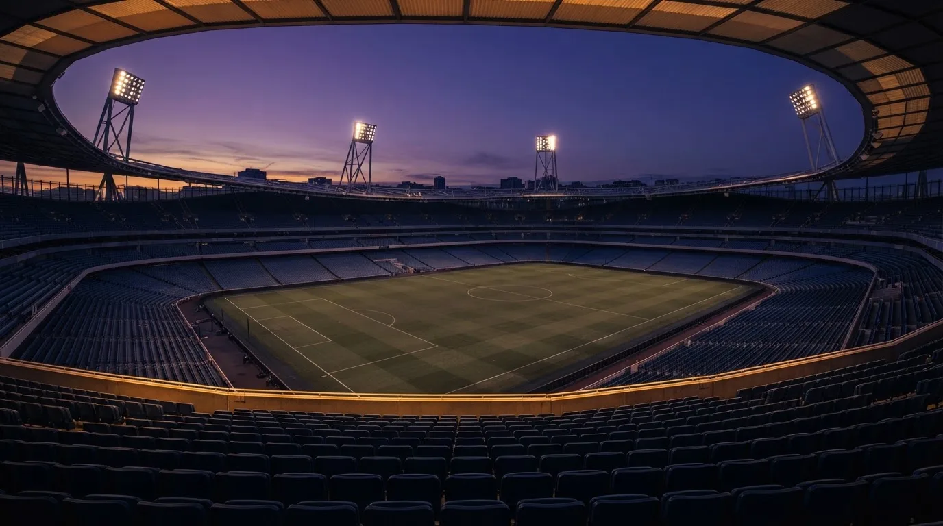 Een leeg voetbalstadion met lichtmasten bij schemering