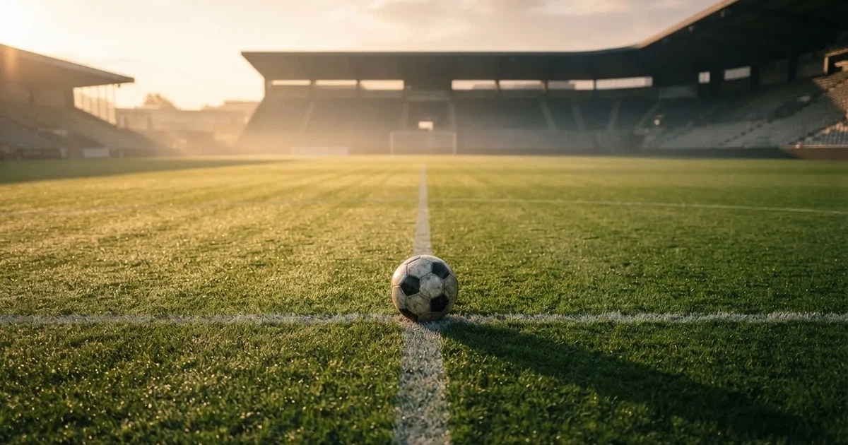 Een voetbal op de middenstip van een grasveld in het ochtendlicht