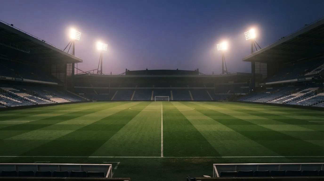 Een leeg voetbalstadion met lichtmasten bij schemering