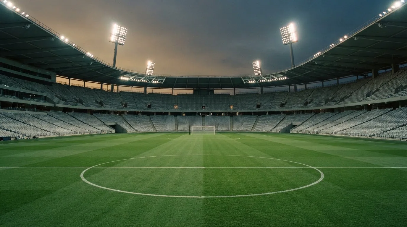 Een leeg voetbalstadion met lichtmasten bij schemering
