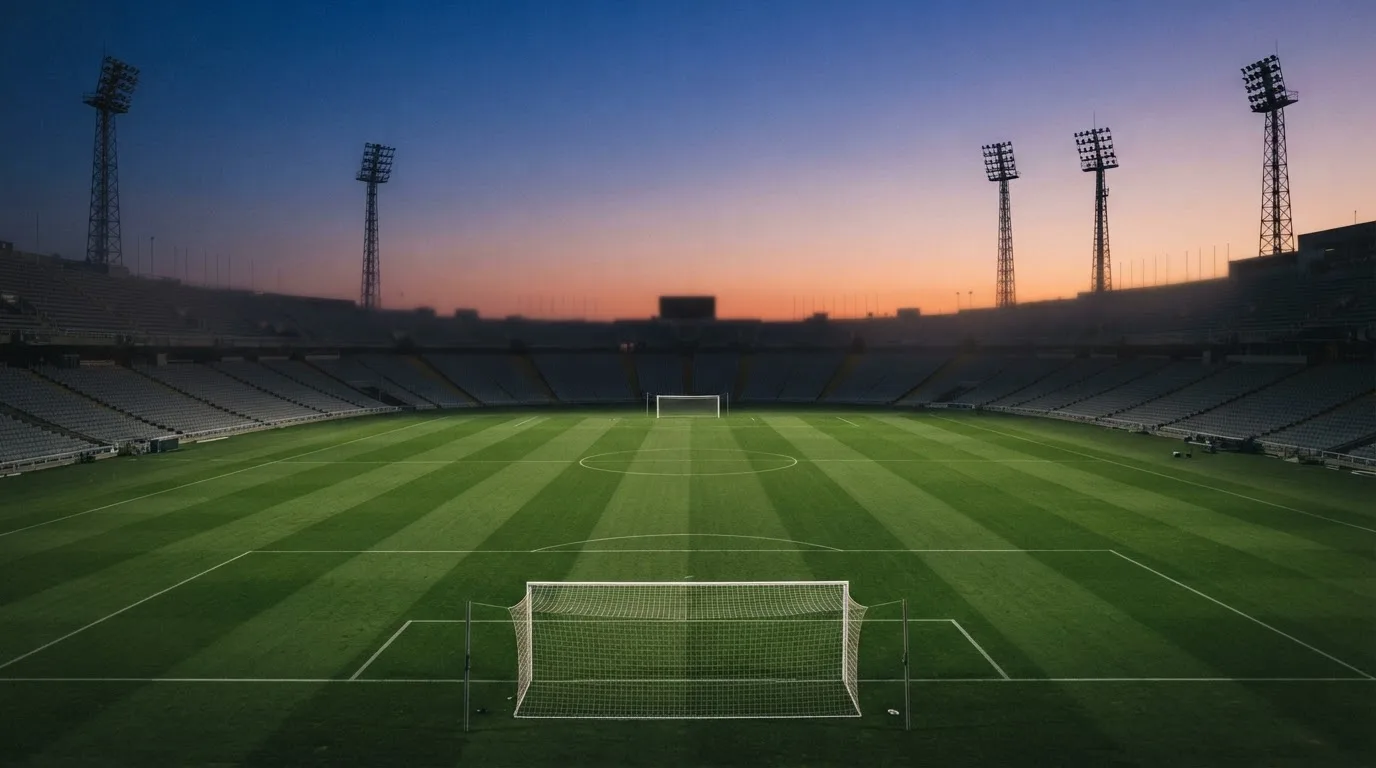 Een leeg voetbalstadion met lichtmasten bij schemering