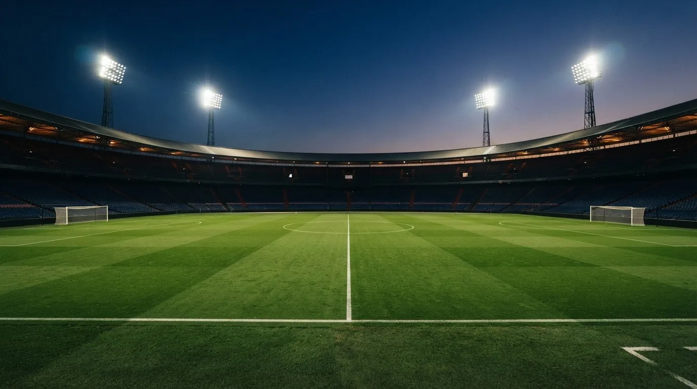 Een leeg voetbalstadion met lichtmasten bij schemering