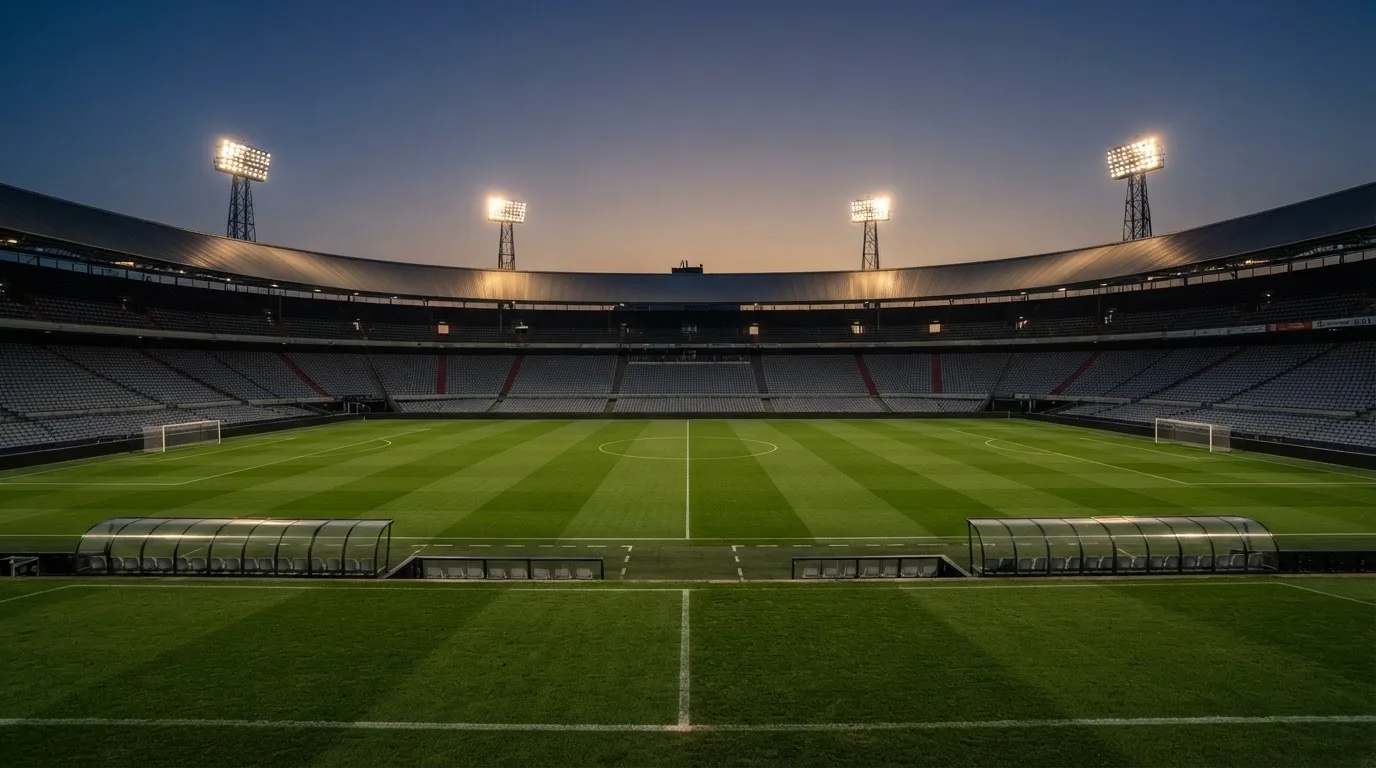 Een leeg voetbalstadion met lichtmasten bij schemering