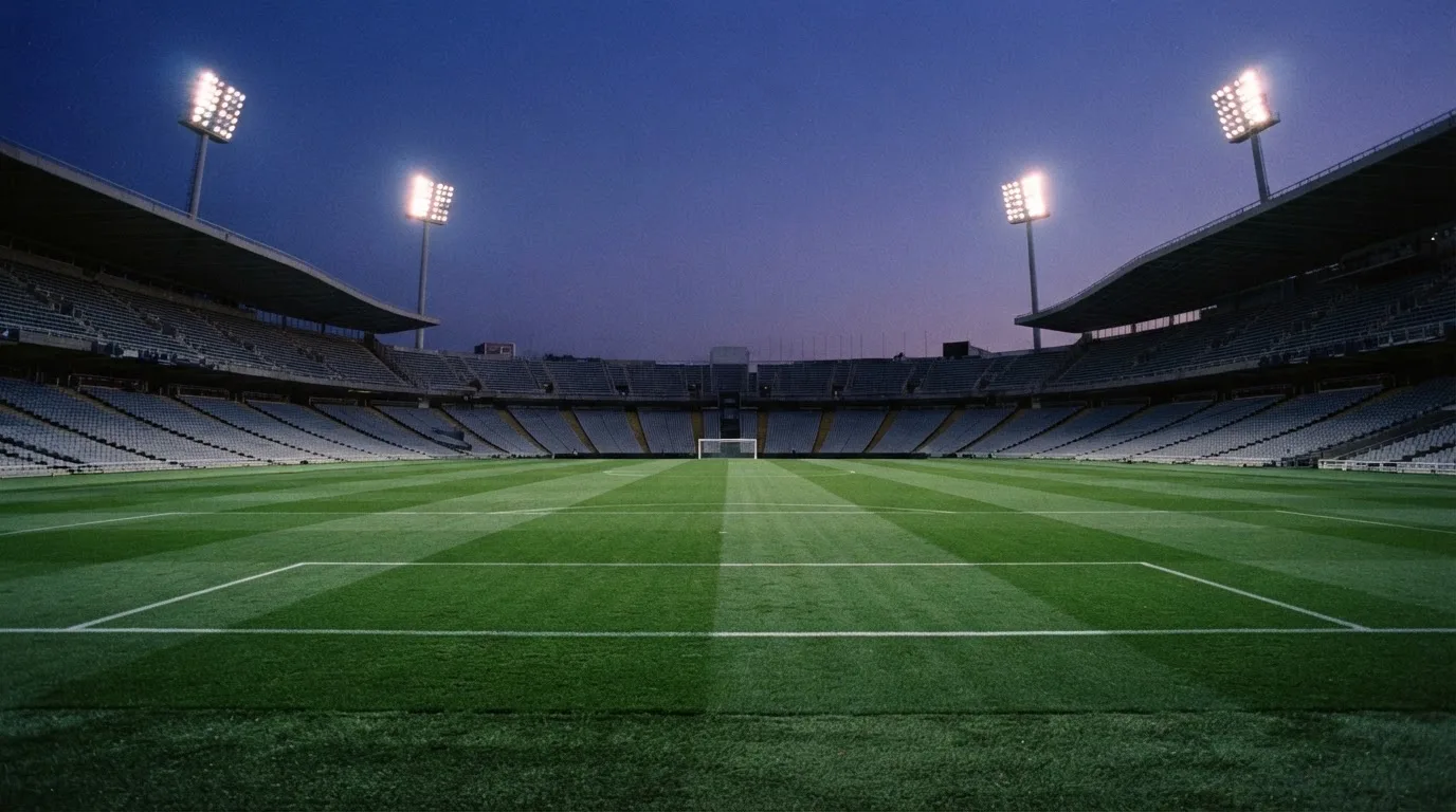 Een leeg voetbalstadion met lichtmasten bij schemering