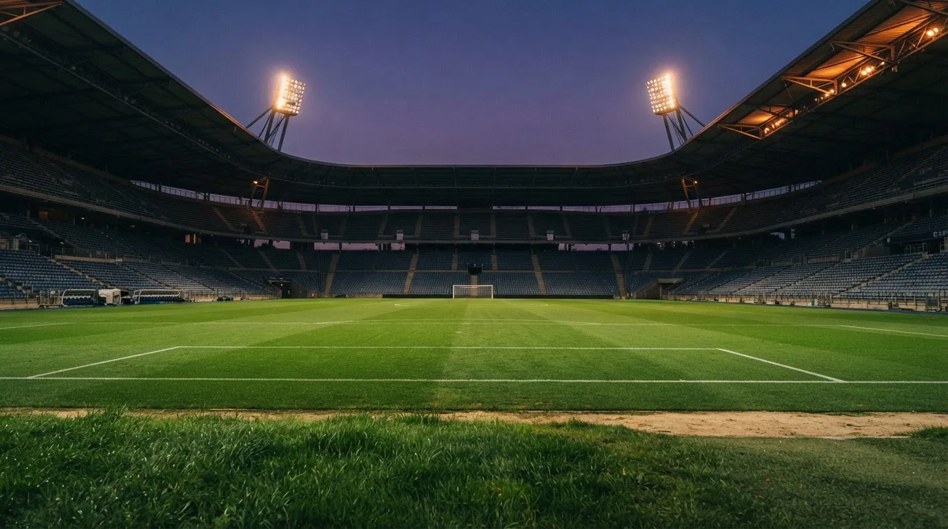 Een leeg voetbalstadion met lichtmasten bij schemering