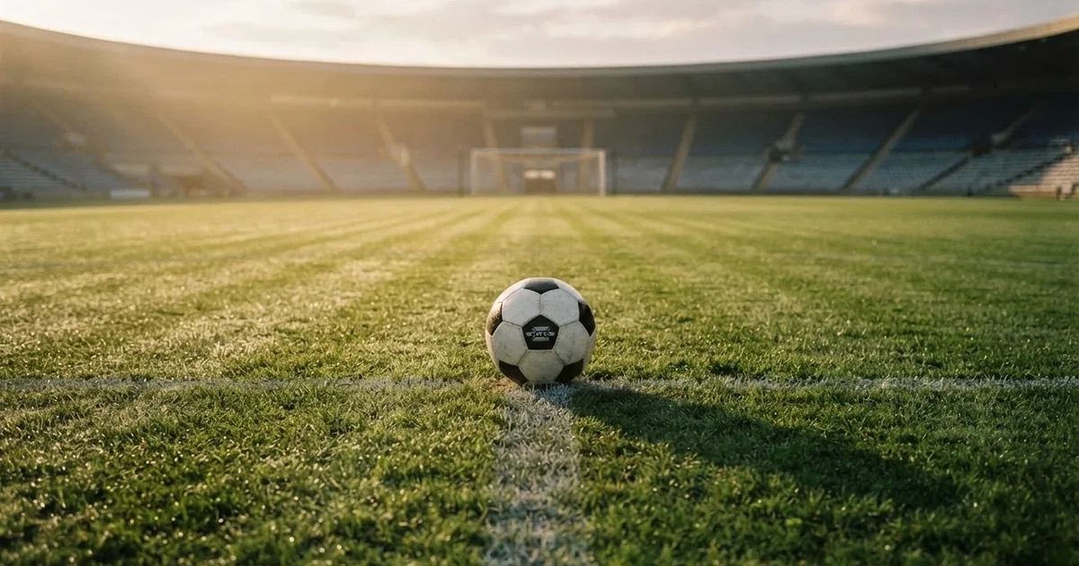 Een voetbal op de middenstip van een grasveld in het ochtendlicht