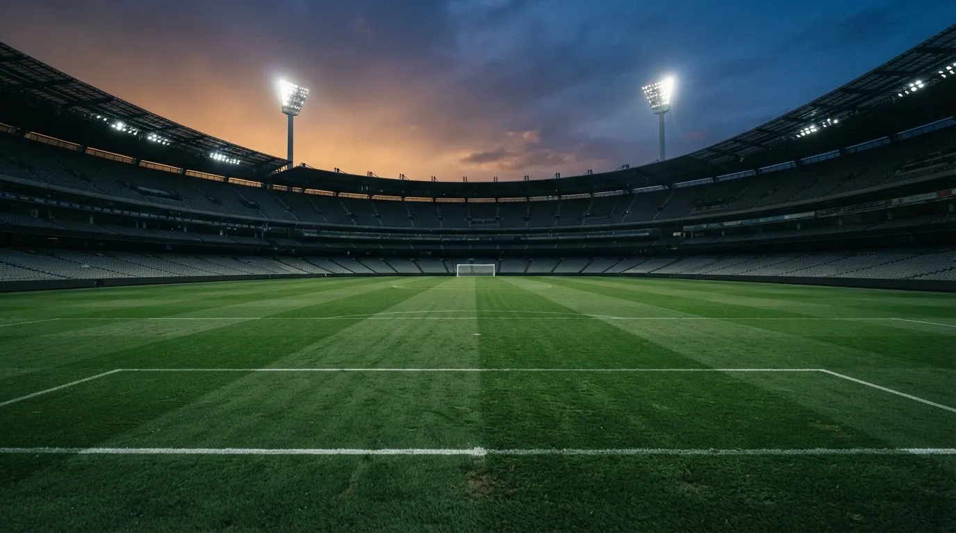 Een leeg voetbalstadion met lichtmasten bij schemering