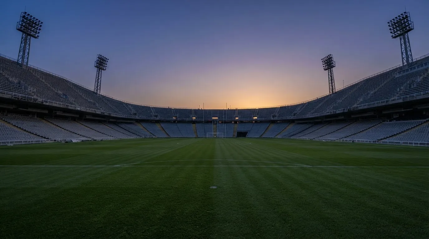 Een leeg voetbalstadion met lichtmasten bij schemering