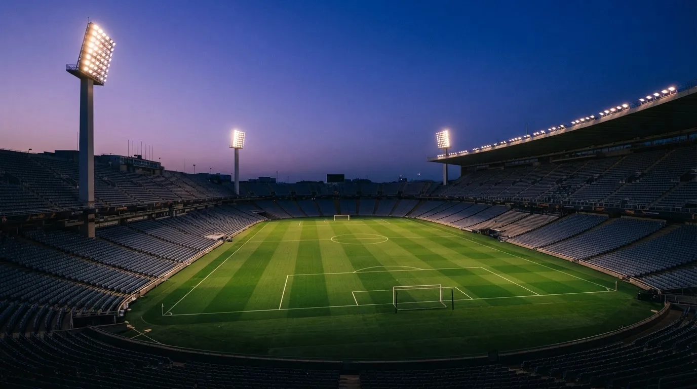 Een leeg voetbalstadion met lichtmasten bij schemering
