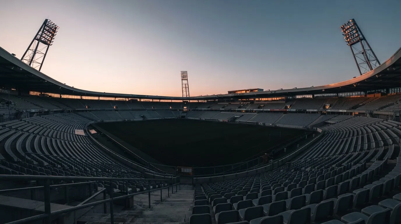 Een leeg voetbalstadion met lichtmasten bij schemering