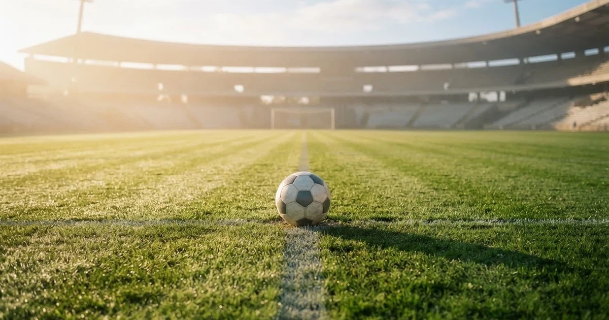 Een voetbal op de middenstip van een grasveld in het ochtendlicht