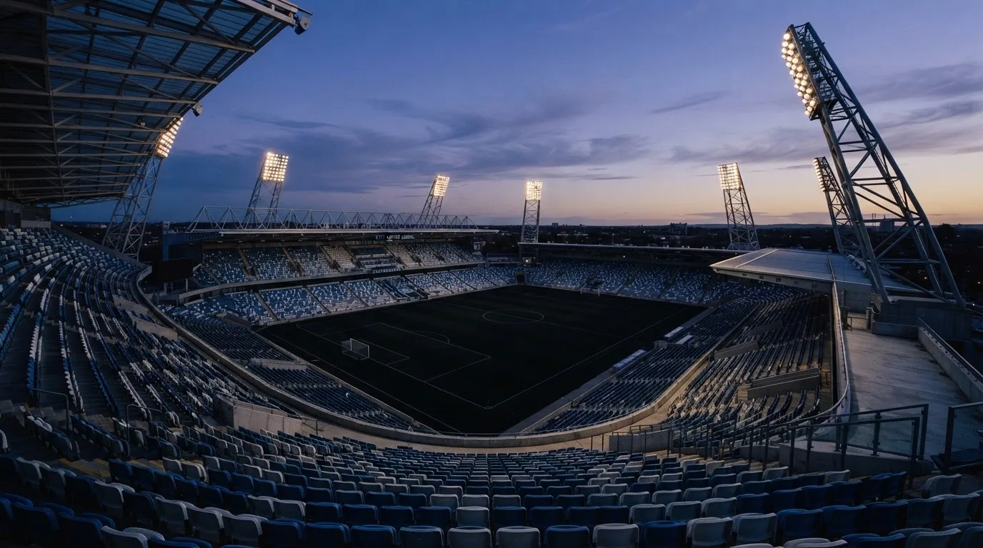 Een leeg voetbalstadion met lichtmasten bij schemering