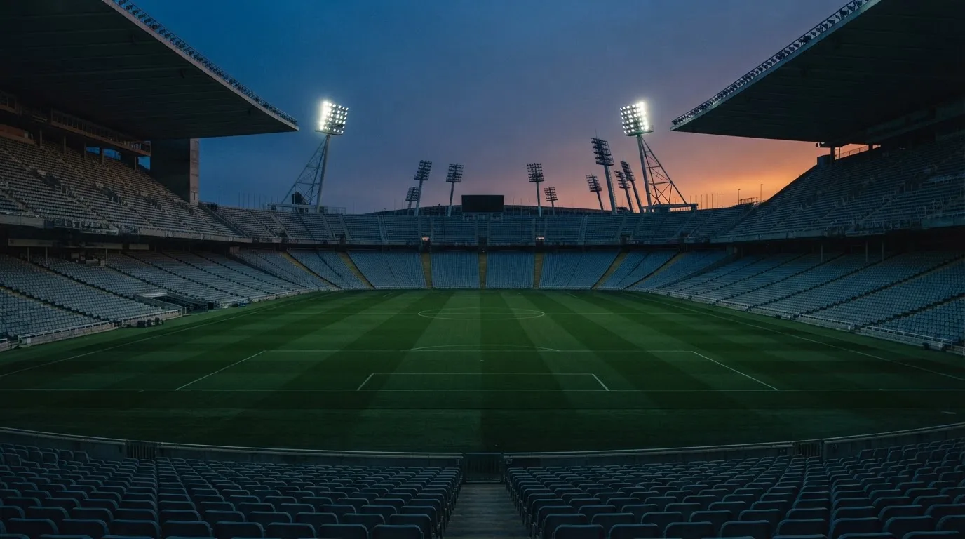 Een leeg voetbalstadion met lichtmasten bij schemering