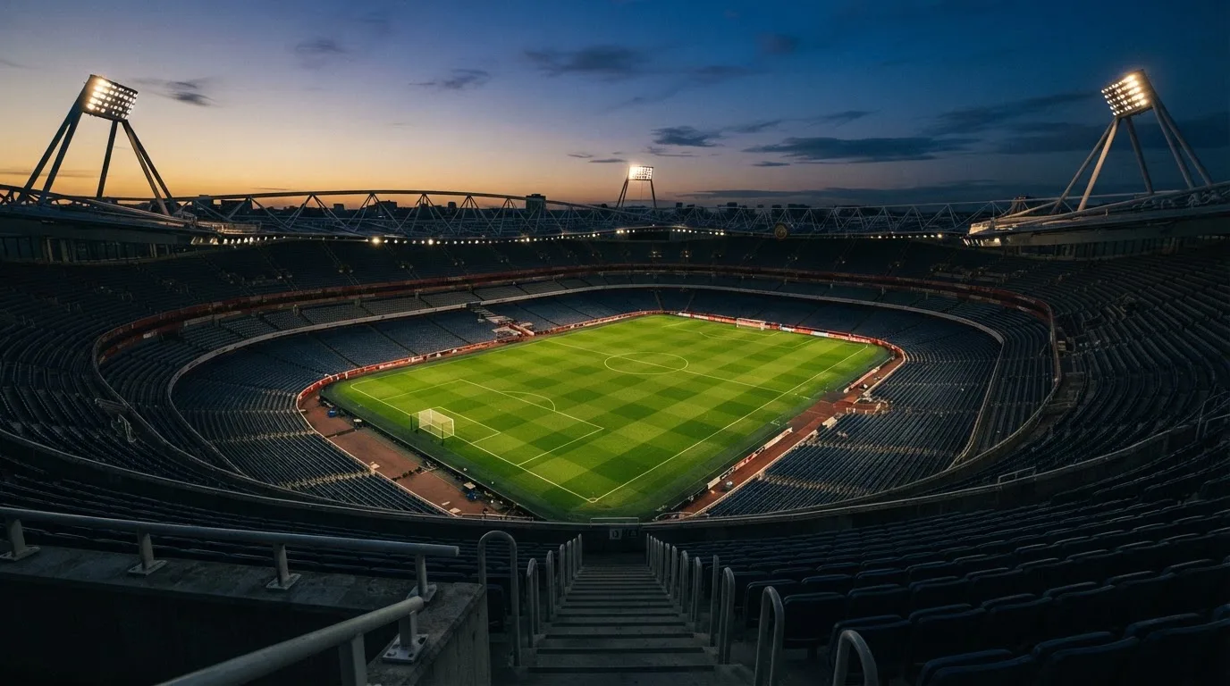 Een leeg voetbalstadion met lichtmasten bij schemering