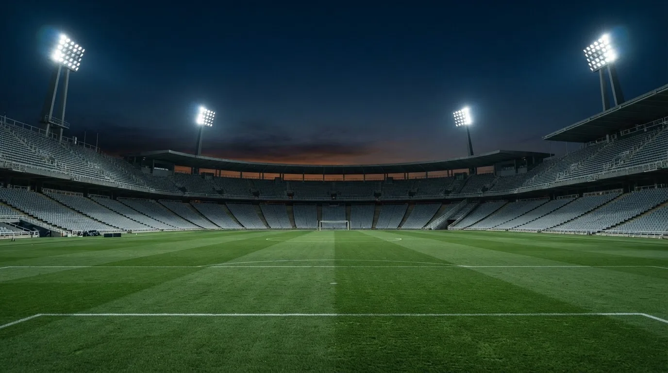 Een leeg voetbalstadion met lichtmasten bij schemering